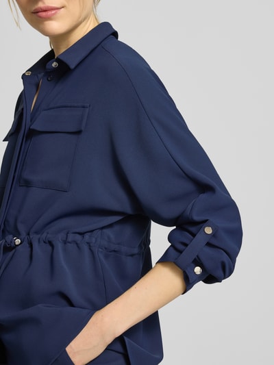Männermodel trägt bluzka koszulowa Regular Fit Hemdbluse mit Brusttaschen Modell 'Februar' von More & More w kolorze granatowym, z tunel w talii, rękaw o dł. 3/4, kołnierzyk koszulowy. Nahaufnahme Oberkörper.