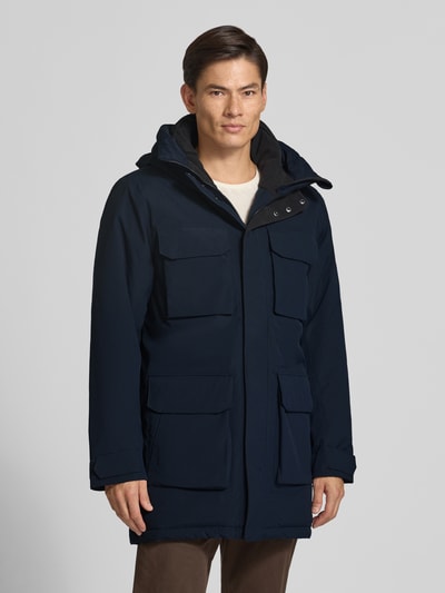 Männermodel trägt dunkelblauen Parka mit Kapuze und Pattentaschen Modell 'AIDEN' von Didriksons, Regular Fit, Ganzkörperansicht von vorne. Rückenlänge 95 cm, Schulterbreite 47 cm, Brustweite 55 cm, Ärmellänge 68 cm.