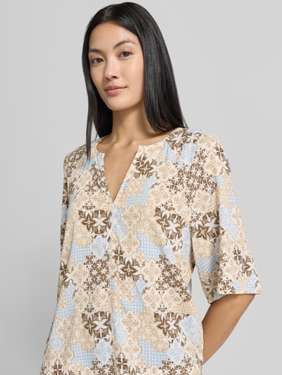 Frauenmodel trägt Relaxed Fit Kurzarmbluse aus Viskose-Mix von s.Oliver RED LABEL mit beigem, blauem und braunem Muster, Nahaufnahme Oberkörper.