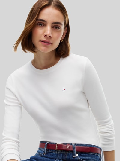 Vrouwenmodel draagt wit slim fit shirt met lange mouwen van katoen, Slim Fit Langarmshirt aus reiner Baumwolle van Tommy Hilfiger, close-up bovenlichaam.