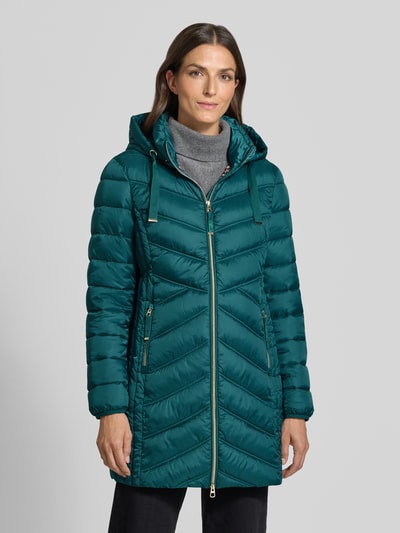 Modelka kobieca nosi Steppmantel mit Zweiwege-Reißverschluss von Christian Berg Woman Selection, kolor morski, krój slim fit, kaptur z troczkiem, kieszenie na zamek, srebrne detale, długość pleców 83 cm, szerokość ramion 40 cm, szerokość klatki piersiowej 48 cm, długość rękawa 65 cm, widok całej sylwetki z przodu.