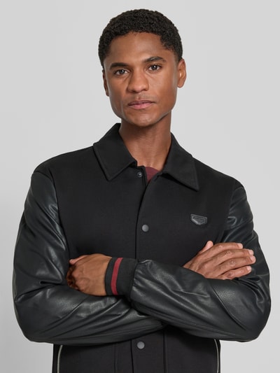 Mannenmodel draagt Sweatjacke mit Kentkragen van Antony Morato, regular fit, zwart, leren mouwen, Nahaufnahme Oberkörper.