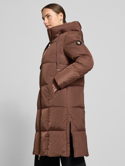 Frauenmodel trägt Regular Fit Mantel in Stepp-Optik Modell 'Nova' von MOS MOSH in Braun mit Kapuze, sichtbaren Nähten und Eingrifftaschen, Nahaufnahme Oberkörper seitlich. Rückenlänge 102 cm, Schulterbreite 42 cm, Brustweite 46 cm, Ärmellänge 64 cm.