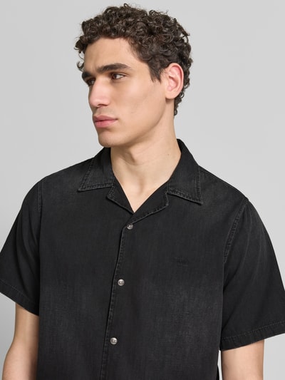 Männermodel trägt Regular Fit Jeanshemd aus Baumwolle von Diesel in Schwarz mit durchgehender Druckknopfleiste und Reverskragen, Nahaufnahme Oberkörper. Kurzärmeliges Herren Freizeithemd aus Reiner Baumwolle, Regular-Fit, Rückenlänge 72 cm, Schulterbreite 44 cm, Ärmellänge 31 cm.