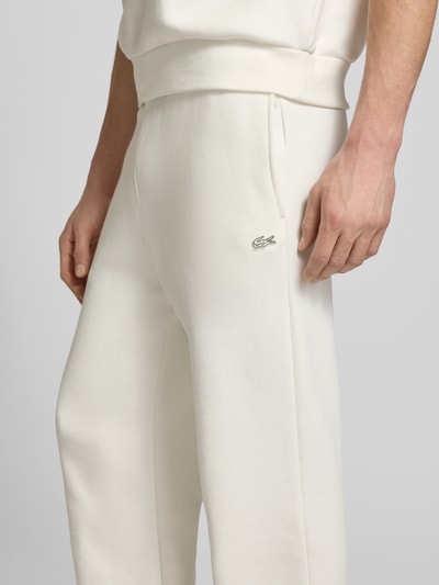 Männermodel trägt Loose Fit Sweatpants aus reiner Baumwolle von Lacoste in Unifarbe mit Logo-Detail, seitlichen Taschen, Nahaufnahme Oberschenkel.