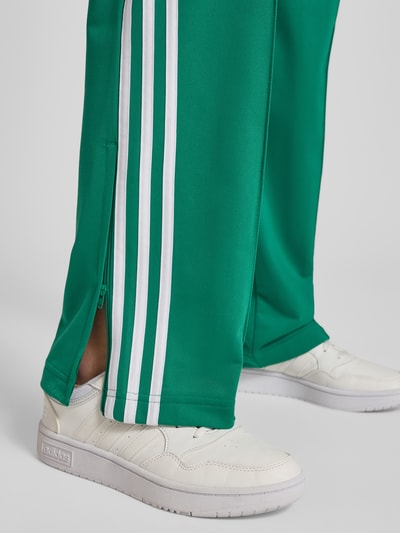 Vrouwenmodel draagt Regular Fit Sweatpants met Logo-Detail model 'FB CLASSIC TP' van adidas Originals, effen groen met witte strepen, sweatstof, detailopname onderbeen.