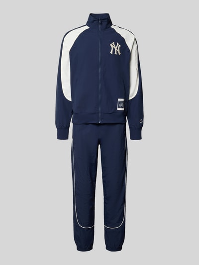 Produktfoto, Relaxed Fit Tracksuit mit Logo-Patch von Champion in dunkelblau mit weißen Kontrasteinsätzen, Reißverschluss, elastische Abschlüsse, sichtbarer Logo-Patch und NY-Schriftzug, Stehkragen, glatte Textur, alle Maße laut Größe M, sportlicher Look.