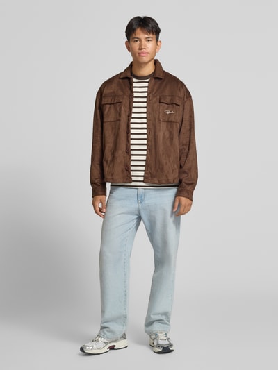 Männermodel trägt Regular Fit Longsleeve aus reiner Baumwolle mit Streifenmuster von JACK & JONES, Farbkombination Creme und Schwarz, Ganzkörperansicht von vorne.