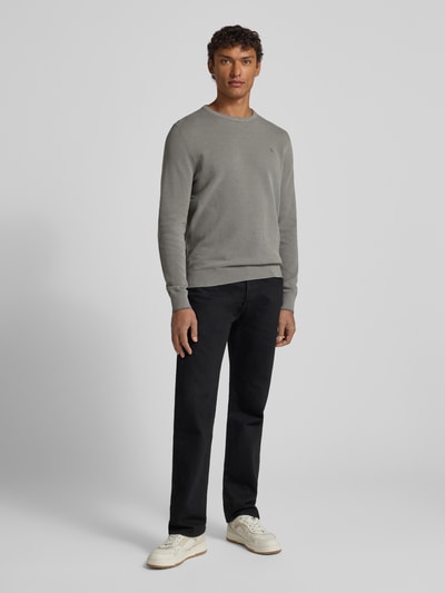Męski model nosi Sweter z dzianiny z wyhaftowanym logo od Lerros, bawełna, krój regular fit, prążkowane wykończenia, okrągły dekolt, kolor szary, długość tyłu 70 cm, długość rękawów 74 cm, widok całej sylwetki z przodu.