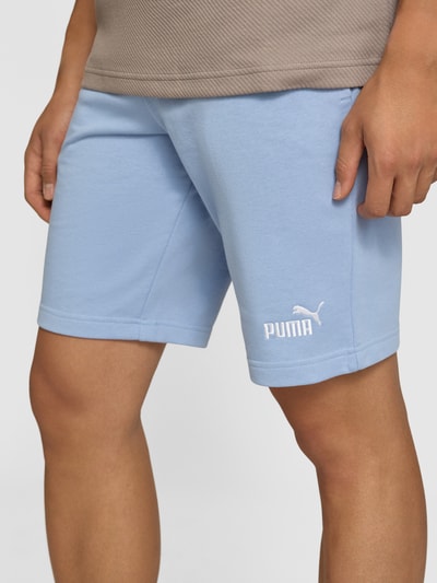Männermodel trägt Shorts mit Logo und elastischem Bund von PUMA in Hellblau, Baumwoll-Mix, Regular Fit, Nahaufnahme Oberschenkel, Kontext: Herren Shorts von PUMA Performance, elastischer Bund, Logo, Bundweite M 39 cm, Innenbeinlänge M 26 cm.