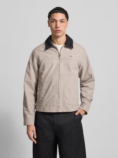 Męski model nosi Regular Fit Ranch-Jacke aus reiner Baumwolle von Tommy Jeans, efekt: jednolity kolor, wykładany kołnierz ze sztruksu, zapięcie na zamek błyskawiczny, wyhaftowane logo, długi rękaw z mankietem, regulacja szerokości, boczne kieszenie zapinane na zamek, bawełna, całkowity widok z przodu.