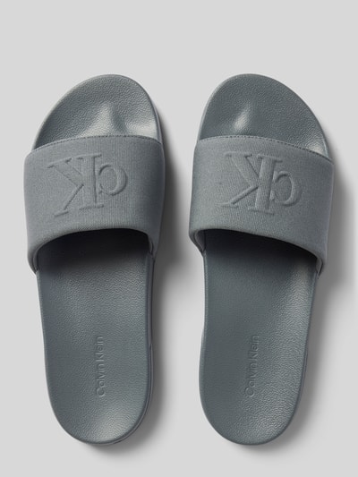 Produktfoto, 'Badeschuhe mit Logo-Detail' von CK Calvin Klein, szary odcień, minimalistyczny design, lekko teksturowana powierzchnia.