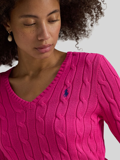 Vrouwenmodel draagt Regular Fit Strickpullover aus Woll-Kaschmir-Mix van Polo Ralph Lauren, felroze, kabelpatroon, logo, close-up bovenlichaam.
