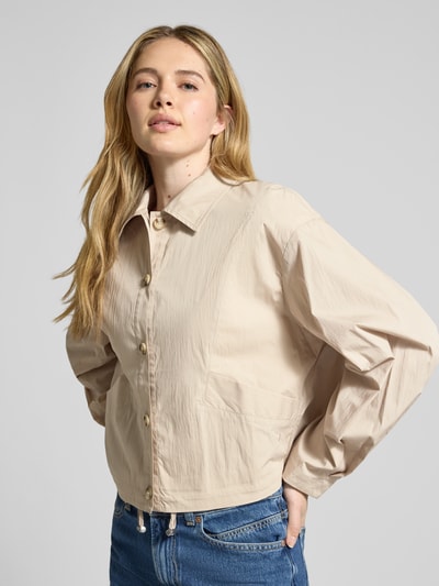 Frauenmodel trägt Cropped Jacke mit Eingrifftaschen von Jake*s Collection in Beige, reine Baumwolle, Knopfleiste, Umlegekragen, Ganzkörperansicht von vorne, Rückenlänge bei Größe 36: 53 cm, Schulterbreite 39 cm, Brustweite 44 cm, Ärmellänge 55 cm.