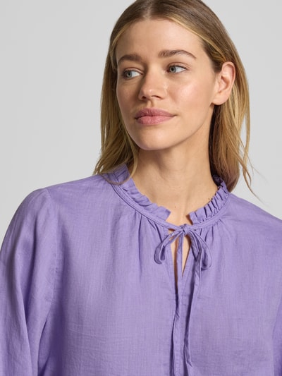 Frauenmodel trägt Leinenbluse mit Serafino-Kragen und Schnürung von Emily Van den Bergh in Lila, Reines Leinen, Loose-Fit, Nahaufnahme Oberkörper.