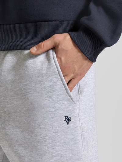 Männermodel trägt Slim Fit Sweatpants mit Logo-Stitching von REVIEW aus Baumwoll-Mix in Hellgrau, Nahaufnahme Oberkörper.