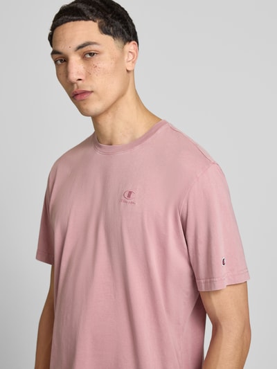 Männermodel trägt T-Shirt mit Label-Stitching und Rundhalsausschnitt von CHAMPION in Rosa, Reine Baumwolle, Regular-Fit, Nahaufnahme Oberkörper. Rückenlänge bei Größe M: 67 cm.