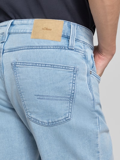Männermodel trägt Regular Fit Jeansshorts aus Baumwoll-Mix von s.Oliver RED LABEL in hellem Denim mit Label Patch, Nahaufnahme Rückansicht.