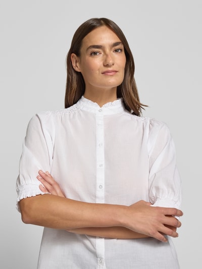 Frauenmodel trägt weiße Regular-Fit Bluse mit Stehkragen Modell 'CALISTE' von Soyaconcept aus Reine Baumwolle, Puffärmel, Knopfleiste, Nahaufnahme Oberkörper. Rückenlänge bei Größe S: 59 cm, Ärmellänge bei Größe S: 38 cm.