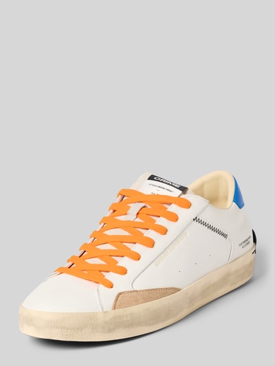 Produktfoto, Sneaker mit Schnürung Modell 'DISTRESSED' von Crime London in Weiß mit orangefarbener Schnürung, Label-Details, Distressed-Look, abgerundete Spitze, Absatzhöhe 4 cm, Schafthöhe 5 cm, Schaftweite 6 cm.
