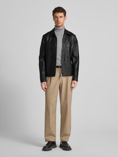 Męski model nosi Slim Fit Kurtkę w imitacji skóry Model 'GIUBBINO' od Antony Morato, kolor czarny, proste linie, kieszenie z patką, zamek błyskawiczny dwustronny, wykładany kołnierz, długość tyłu w rozmiarze 50: 66 cm, szerokość ramion w rozmiarze 50: 42 cm, szerokość w rozmiarze 50: 50 cm, długość rękawów w rozmiarze 50: 67 cm. Ganzkörperansicht von vorne.