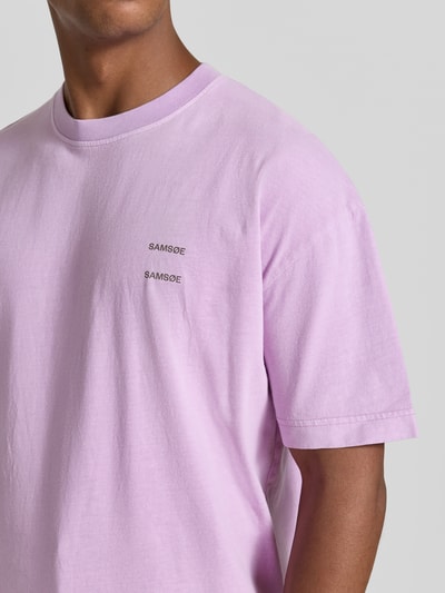 Mannenmodel draagt lila Oversized T-Shirt uit pure katoen Modell 'Joel' van Samsøe Samsøe met logo-print, ronde hals, detailopname borst.
