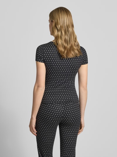 Frauenmodel trägt Damen T-Shirt mit Rundhalsausschnitt Modell 'DESTINY' von Noisy May, Material-Mix mit Stretch-Anteil, Slim-Fit, schwarze Farbe mit weißen Punkten, Rückenlänge bei Größe S 51 cm, Ganzkörperansicht Rückansicht.