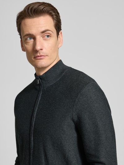 Męski model nosi Regular Fit Cardigan mit Stehkragen od OLYMP Level Five, czysty bawełniany, struktura dzianiny, zamek, elastyczne wykończenia, długość tyłu 68 cm, długość rękawa 67 cm, krój regular fit, zdjęcie zbliżenie górnej części ciała.