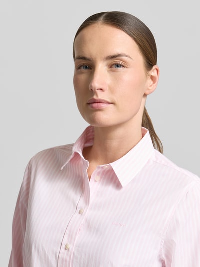 Kobieta modelka nosi Regular Fit Bluse mit Streifenmuster und Label-Stitching von Gant, bawełna, kołnierzyk koszulowy, krój regular fit, jasnoróżowe paski, delikatna tekstura, długość pleców w rozmiarze 36: 65 cm, długość rękawa w rozmiarze 36: 61 cm, zbliżenie na górę ciała