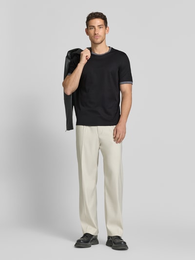 Męski model nosi T-Shirt mit Rundhalsausschnitt od bugatti, bawełniany mix, krój regular fit, detal z logo, czarny, gładka tekstura, widok całej sylwetki z przodu, długość tyłu w rozmiarze M: 70 cm.