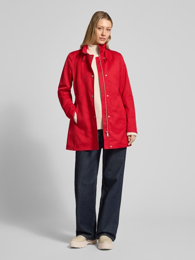 Frauenmodel trägt roten Trenchcoat mit Stehkragen und Eingrifftaschen von Fuchs Schmitt, Baumwoll-Mix, Ganzkörperansicht von vorne.