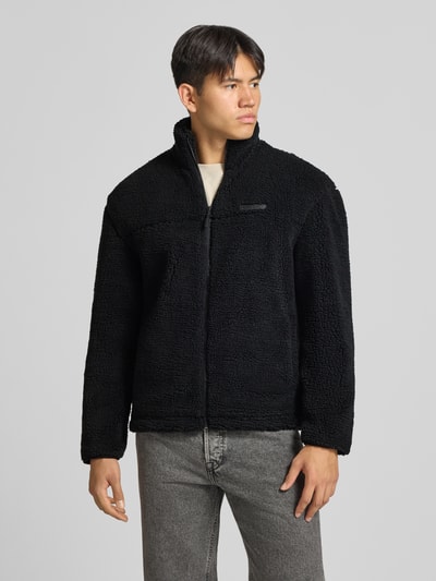 Männermodel trägt schwarze Fleecejacke mit Label-Detail und Reißverschluss von REVIEW, Teddyfell, Regular Fit, Ganzkörperansicht von vorne.