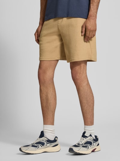 Männermodel trägt Shorts aus Baumwoll-Mix mit Strukturmuster Modell 'KNOX' von Redefined Rebel in Beige, Relaxed Fit, Ganzkörperansicht von vorne.