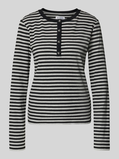 Frauenmodel trägt Longsleeve mit Henley-Kragen von MYON, schwarz-weiß gestreift, Ripp-Struktur, tailliert, Baumwoll-Elasthan-Mix, Ganzkörperansicht von vorne.