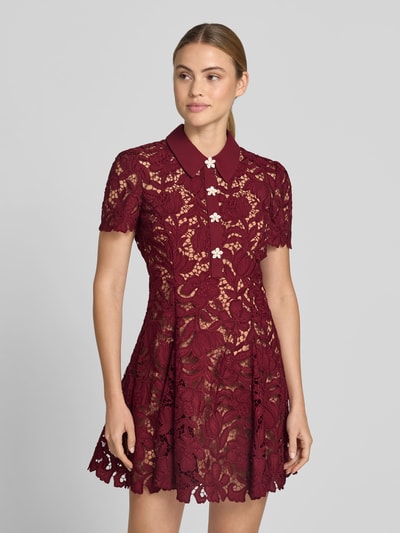 Frauenmodel trägt Minikleid mit Allover-Spitzenbesatz von Self-Portrait in Dunkelrot mit Umlegekragen, taillierter Passform und Unterkleid, Ganzkörperansicht von vorne.