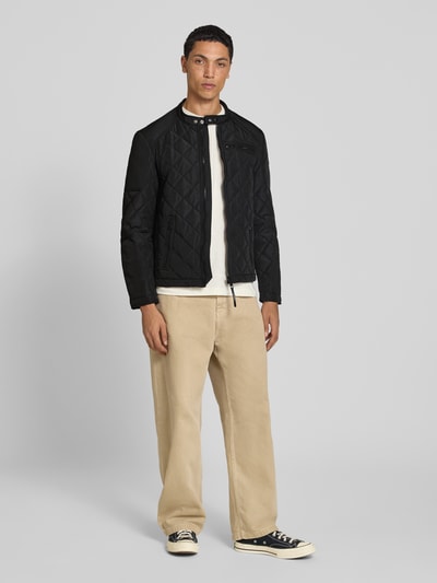Männermodel trägt Regular Fit Jacke in Stepp-Optik von Replay in Schwarz, mit Reißverschlusstaschen und Stehkragen, Ganzkörperansicht von vorne.