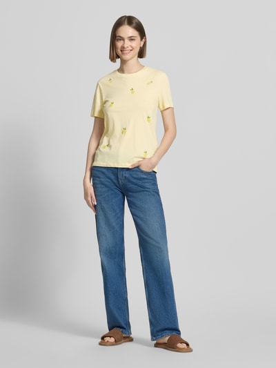 Frauenmodel trägt Regular Fit T-Shirt aus reiner Baumwolle Modell 'KITA' von Only in Optik: Unifarben mit Motiv-Stitching, Rundhals, Kurzarm aus Jersey, helle Gelbtöne, glatte Textur, Ganzkörperansicht von vorne.