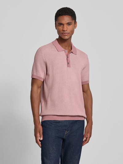 Męski model nosi koszulkę polo Slim Fit Poloshirt mit Strukturmuster Modell 'Brianoro' von JOOP! COLLECTION z bawełny, fakturowany wzór, listwa guzikowa, detal z logo, długość tyłu w rozmiarze M: 70 cm, różowe odcienie, przedni widok całej sylwetki.