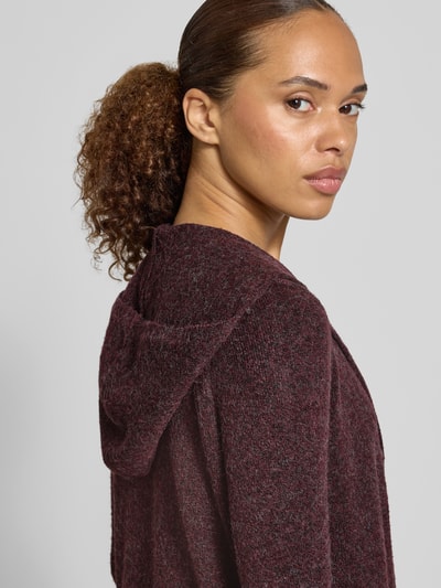 Frauenmodel trägt Regular Fit Cardigan mit Kapuze Modell 'DOFFY' von VERO MODA in meliertem Dunkelrot, strukturierte Oberfläche, Nahaufnahme Oberkörper.