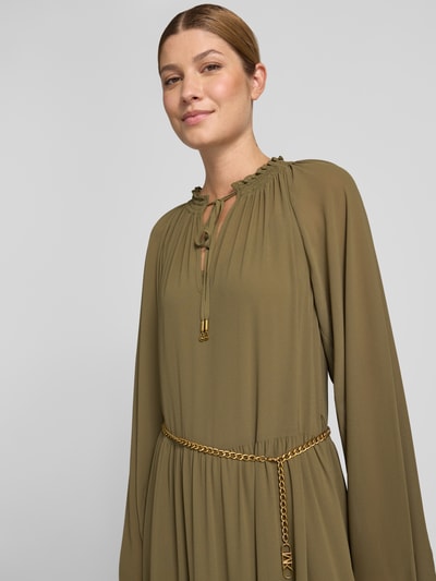 Kobiece modelka nosi długa sukienka Maxikleid im Stufen-Look mit Gürtel od MICHAEL Michael Kors z szyfonu w odcieniu oliwkowym, taliowany krój, ozdobny pasek, efekt stopniowania, okrągły dekolt z wiązaniem, Długość tyłu w rozmiarze S: 135 cm, Szerokość w rozmiarze S: 50 cm, Długość rękawów w rozmiarze S: 74 cm, zbliżenie na górną część sylwetki.