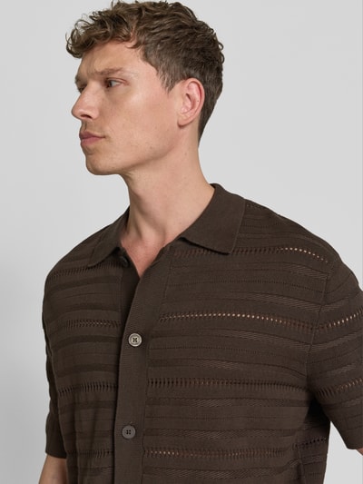 Männermodel trägt Regular Fit Strickjacke aus reiner Baumwolle Modell 'PALLE' von SELECTED HOMME in Braun mit Strukturmuster, Nahaufnahme Oberkörper.