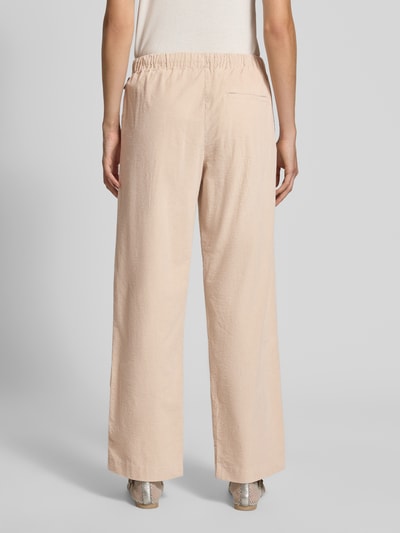 Frauenmodel trägt Relaxed Fit Weite Hose aus Baumwoll-Mix Modell 'JAIMILAA' von ARMEDANGELS in Beige, lockere Form, Damen Weite Hose, Ganzkörperansicht Rückansicht.
