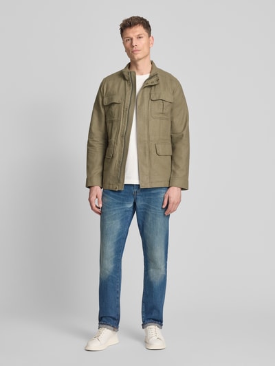 Männermodel trägt Regular Fit Jacke aus Leinen-Mix mit Stehkragen von Geox, Farbe Oliv, vier AufgesetzteTaschen, Langärmelig, Ganzkörperansicht von vorne, Leinen-Baumwoll-Anteil, Rückenlänge 73 cm, Schulterbreite 44 cm, Brustweite 55 cm, Ärmellänge 66 cm, Größe M.