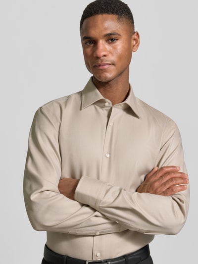 Männermodel trägt Slim Fit Businesshemd aus reiner Baumwolle Modell 'HANK' von BOSS in Beige, Langarm, Kentkragen, Nahaufnahme Oberkörper.