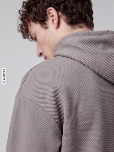 Männermodel trägt Comfort Fit Hoodie aus Baumwoll-Mix Modell 'ESS ELEVATED' von PUMA, strukturierte beige Oberfläche, Nahaufnahme Rückansicht, Herren Hoodie von PUMA Performance, KI-modifiziertes Bild.
