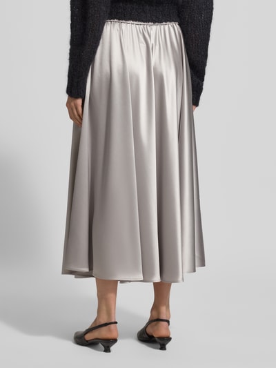 Frauenmodel trägt Midirock aus Satin mit elastischem Bund von HERZENS, A-Linie, fließender Stoff, silbergraue Farbe, Ganzkörperansicht Rückansicht.
