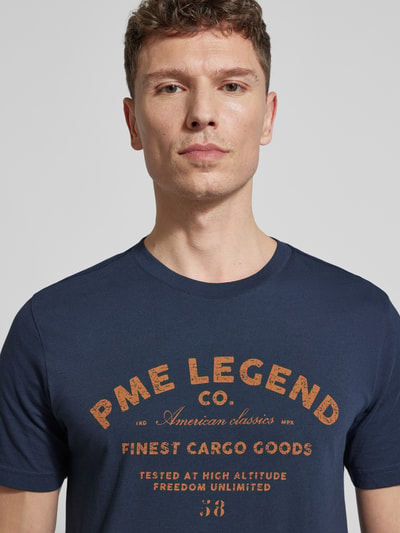 Mannenmodel draagt Regular Fit T-Shirt met Logo-Print van PME Legend, zuiver katoen, regular fit, ronde hals, logo-opdruk, borstlengte maat M: 74 cm, close-up bovenlichaam.