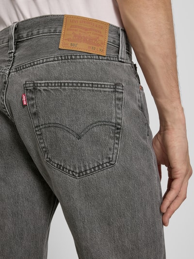 Männermodel trägt Straight Fit Jeans aus reiner Baumwolle Modell '501®' von Levi's®, graue Denim-Optik mit Label-Patch und 5-Pocket-Design, Nahaufnahme Rückansicht.