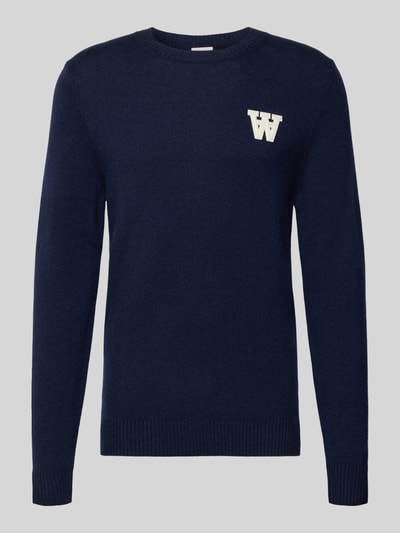 Produktfoto, dunkelblauer Strickpullover aus Lammwolle Modell 'Tay' von Wood Wood, Regular-Fit, cremefarbenes Label-Stitching, Rundhalsausschnitt