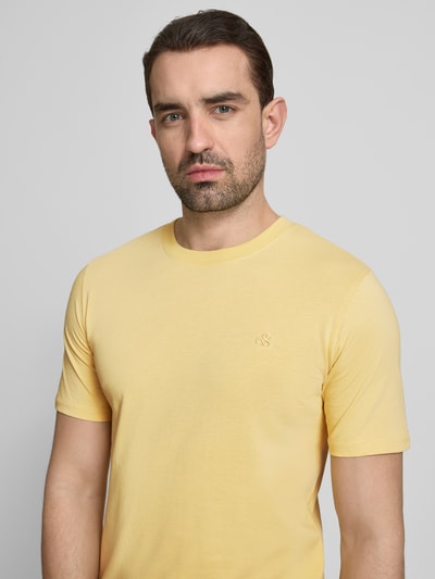 Männermodel trägt Regular Fit T-Shirt mit Logo-Stitching von Scotch & Soda in Gelb aus Reine Baumwolle, Nahaufnahme Oberkörper. Herren T-Shirt mit Rundhalsausschnitt, Rückenlänge bei Größe M 69 cm.